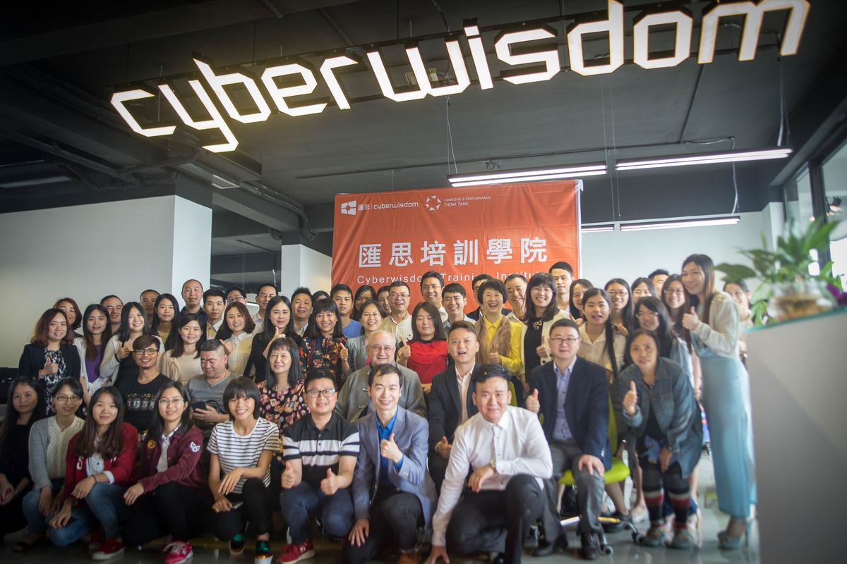 The Cyberwisdom team gathered for a group photo beneath the illuminated Cyberwisdom sign